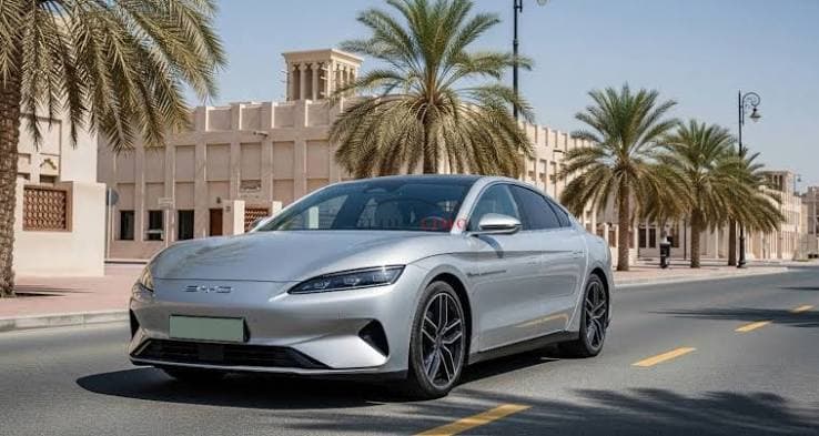 Vue extérieure avant trois-quarts de la BYD Han dans une rue de Dubaï bordée de palmiers