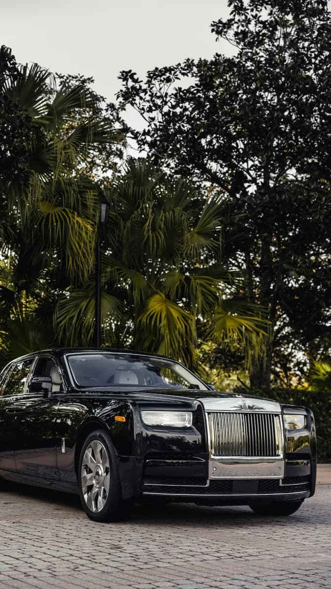 Black Rolls-Royce Phantom chauffeur car front exterior view with palm trees