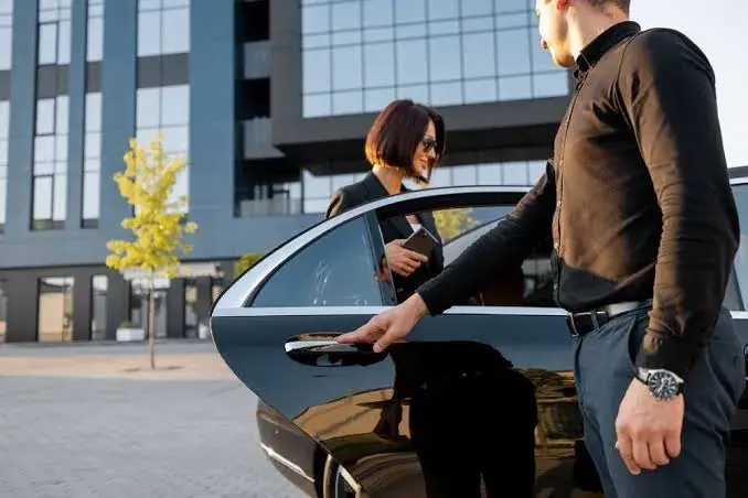 Apex Limo chauffeur opening the car door for a client outside an office building