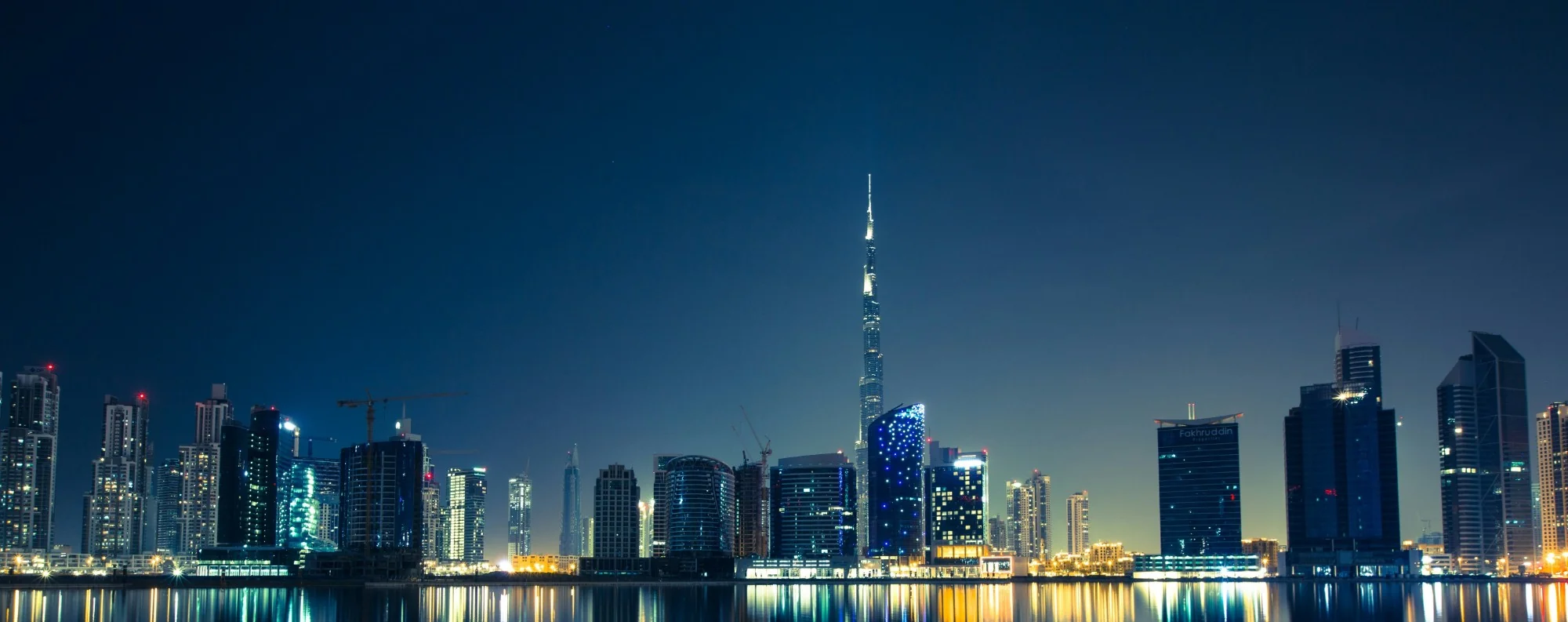 Panoramic night skyline of Downtown Dubai with the Burj Khalifa illuminated above the waterfront
